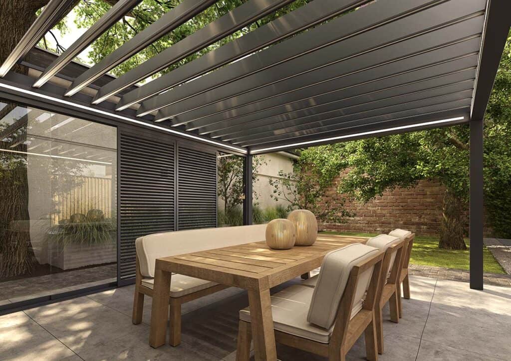 Terrassenüberdachung mit teilweise geöffnetem Lamellendach und LED-Profilen, seitliche Innenansicht, Esstisch im Freien