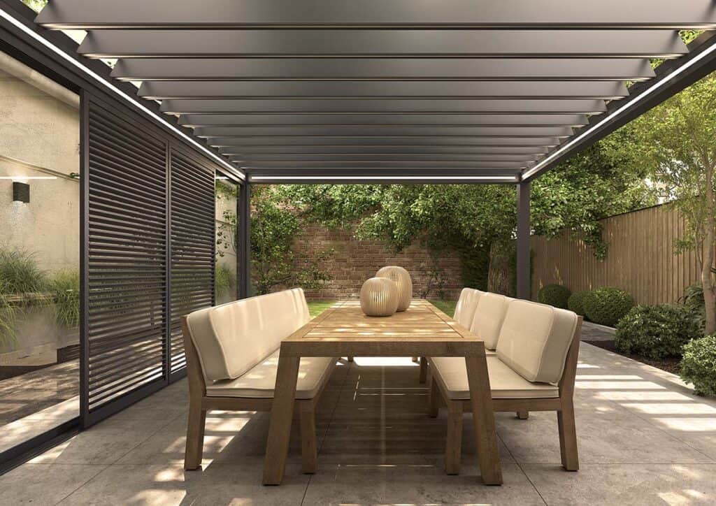 Terrassenüberdachung mit Lamellendach und LED-Beleuchtung von innen, Esstisch aus Holz, Blick in den Garten
