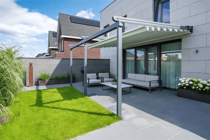 Moderne anthrazitfarbene Faltmarkise von Gartenlüx über einer Terrasse mit grauen Lounge-Möbeln und Garten.