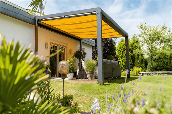 Freistehende Gartenlüx Faltmarkise mit gelbem Tuch und anthrazitfarbenem Aluminiumgestell in einem mediterranen Garten.